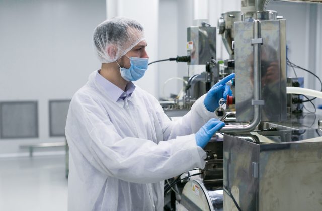 worker on factory in white suit working with manufacture machine